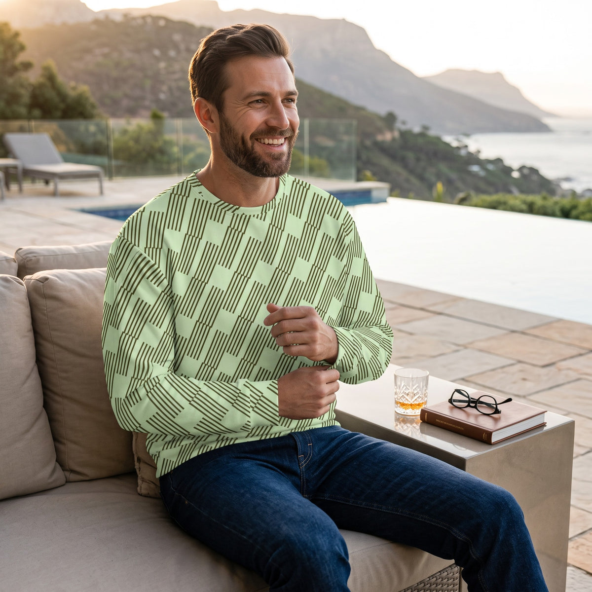 Good Wishes 365 unisex sweatshirt in mint green with dark geometric print, worn by a man sitting by a pool.