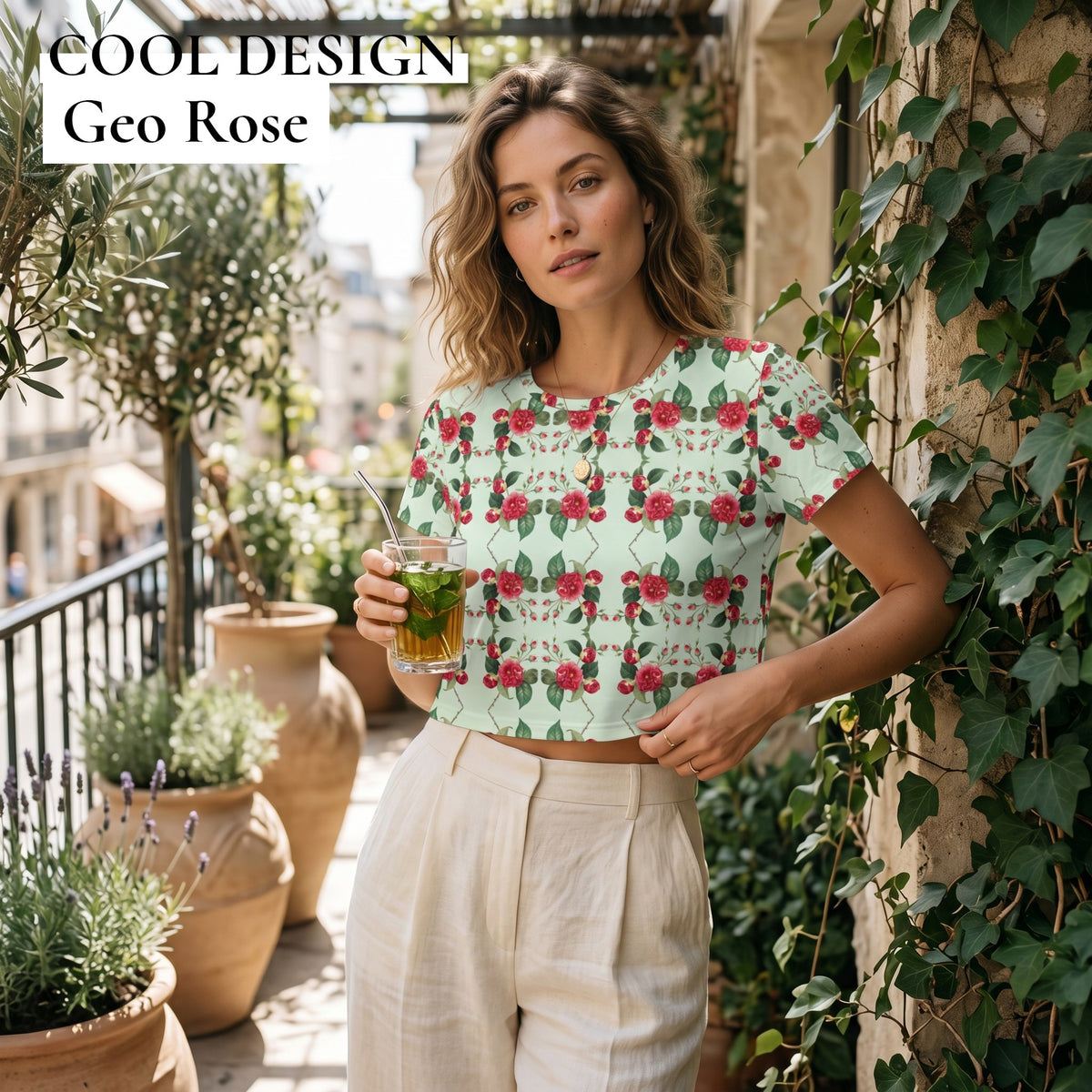 Good Wishes 365 women's mint green crop tee with red rose floral print, worn by a woman on a sunny outdoor terrace.