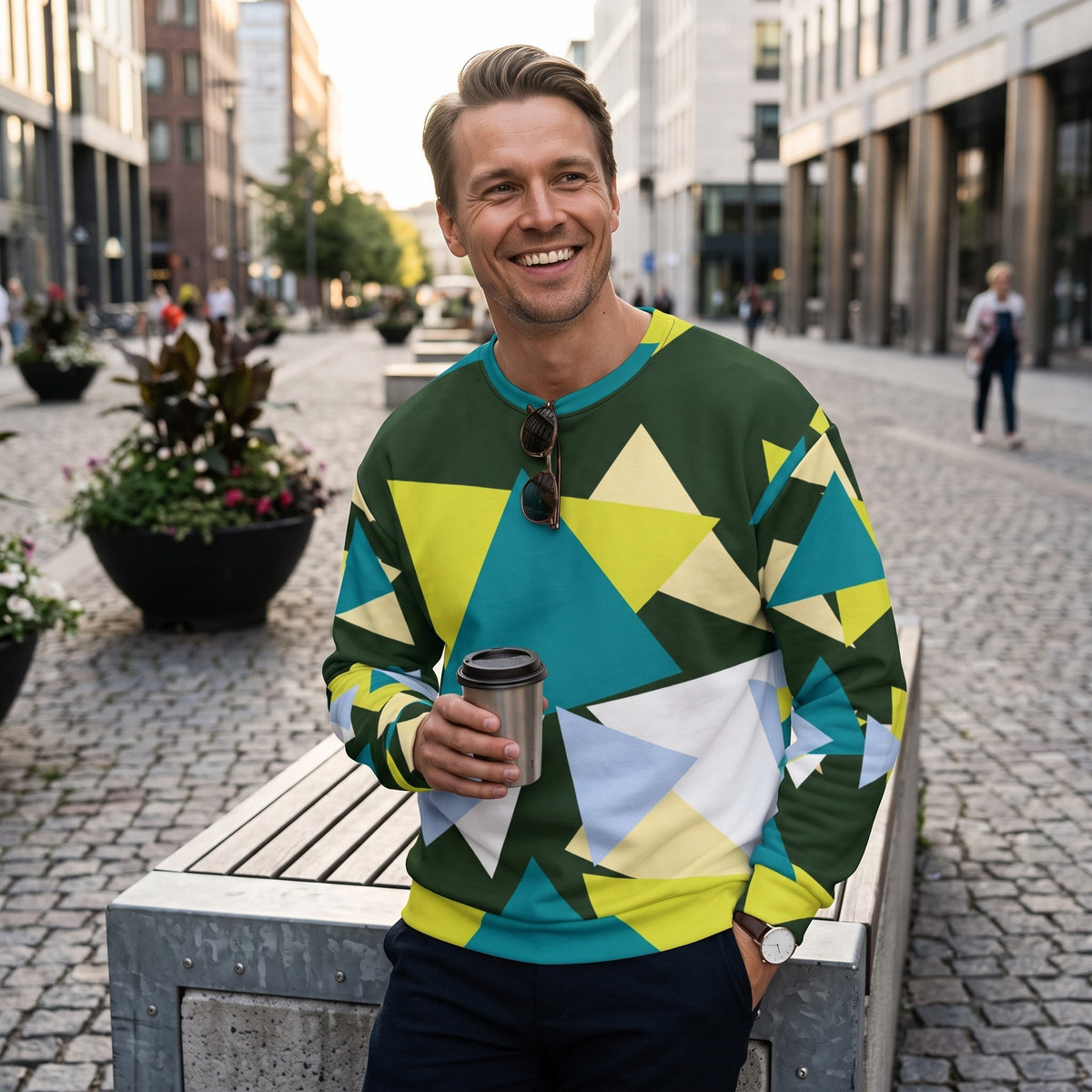 Good Wishes 365 myrtle green sweatshirt with abstract triangle print worn by a smiling man holding a coffee cup