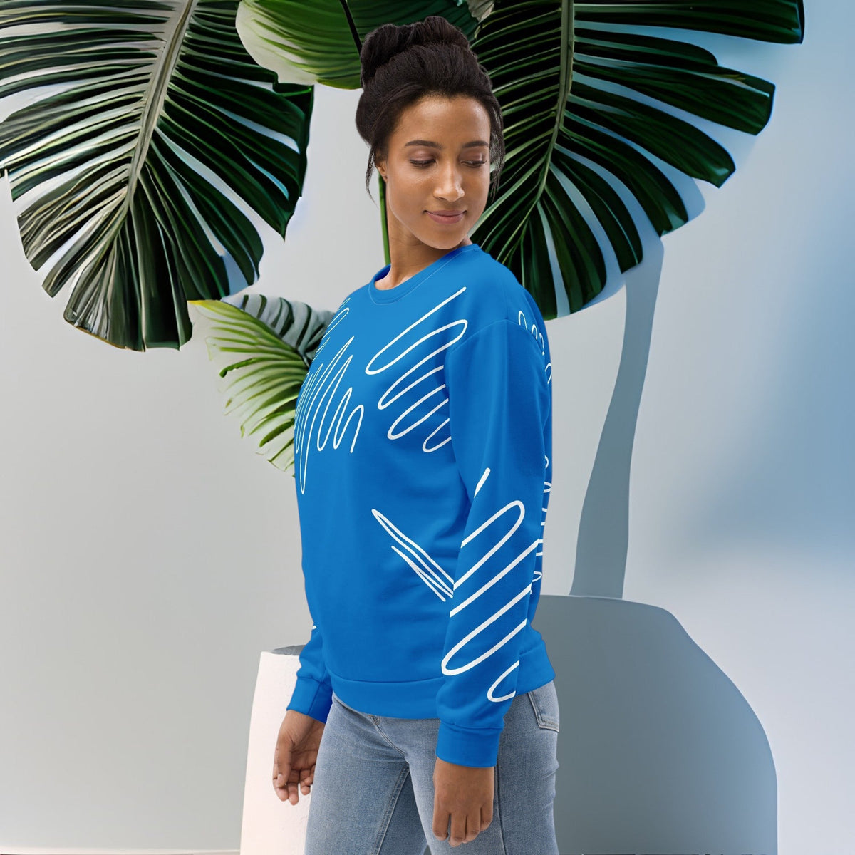 Good Wishes 365 navy blue recycled sweatshirt with white abstract scribble lines worn by a woman near a large plant