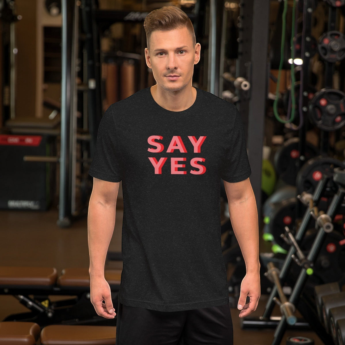 Good Wishes 365 unisex navy graphic t-shirt with coral Say Yes text worn by a man in a gym setting