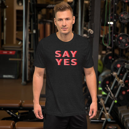 Good Wishes 365 unisex navy graphic t-shirt with coral Say Yes text worn by a man in a gym setting