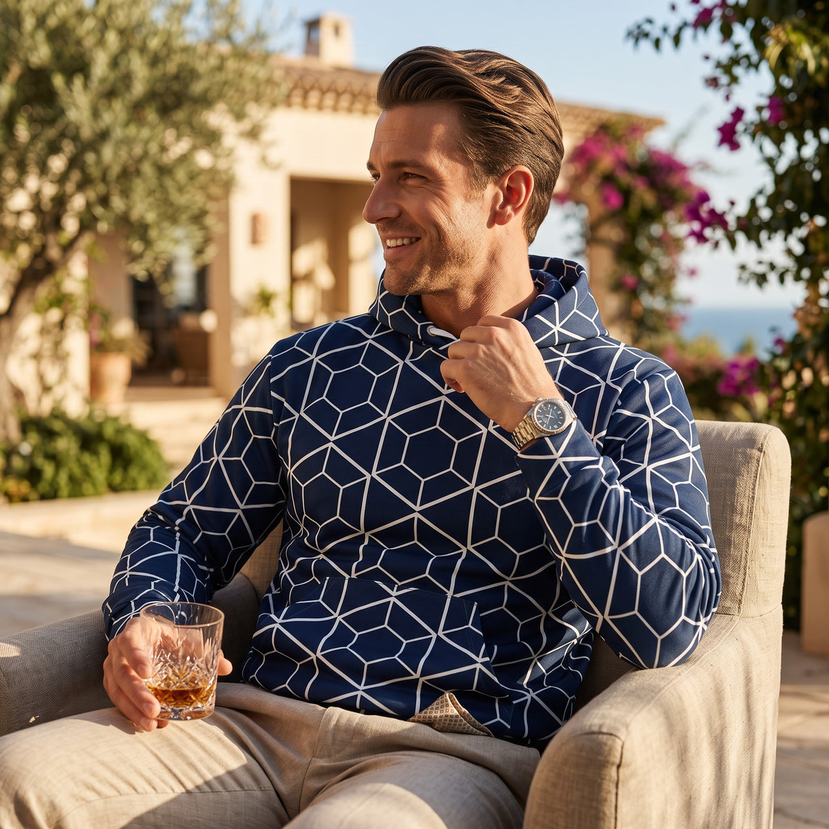Good Wishes 365 navy recycled hoodie with white geometric hexagon print worn by a man sitting in a sunny garden