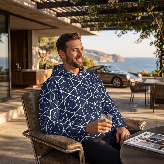 Good Wishes 365 navy recycled hoodie with white geometric hexagon print worn by a man on a sunny outdoor patio.