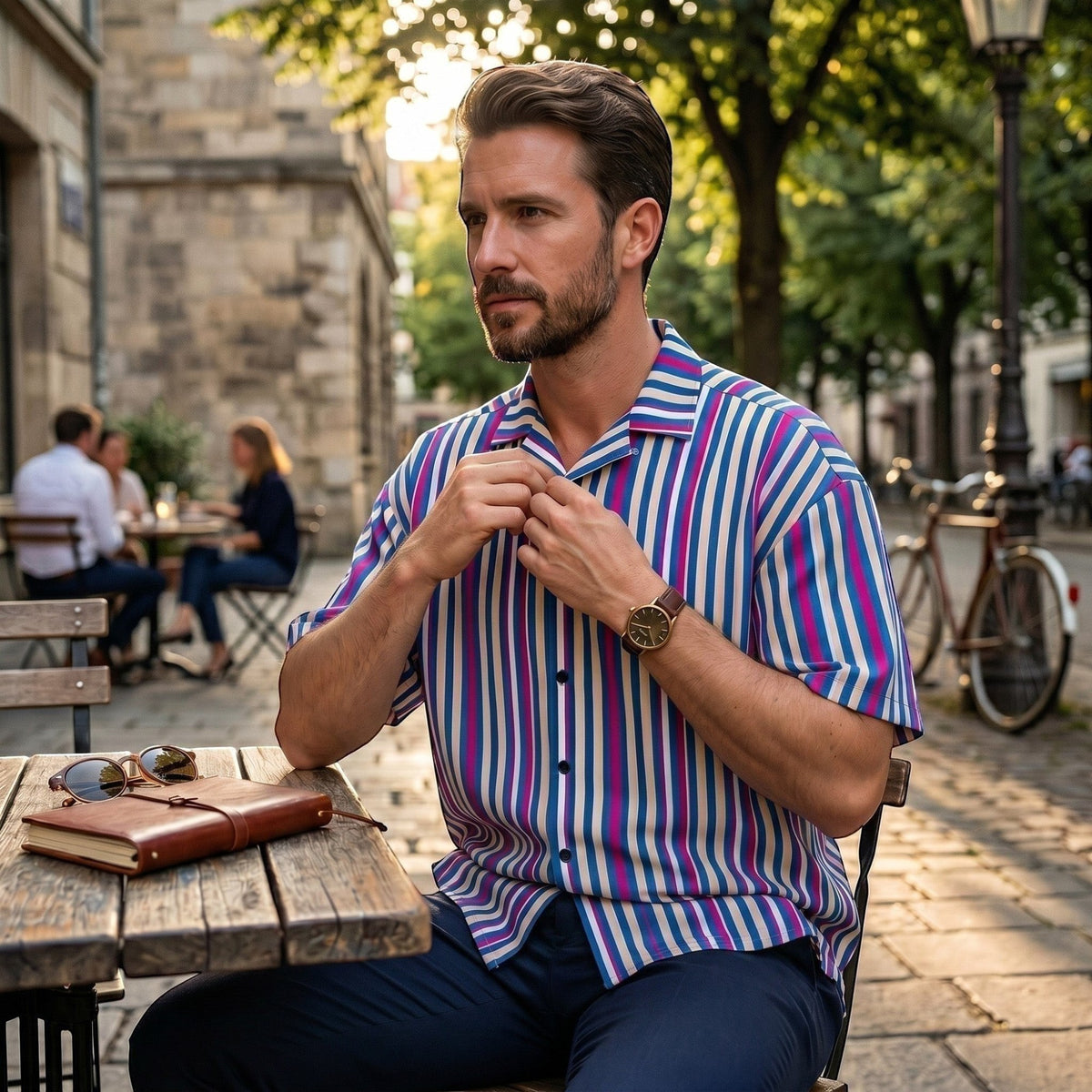 Good Wishes 365 navy blue striped short sleeve button shirt with magenta and white accents on a man at a cafe