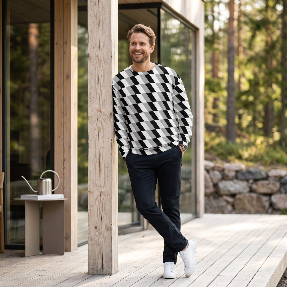 Good Wishes 365 unisex sweatshirt with black, white, and gray optical illusion print worn by a man on a wooden deck.
