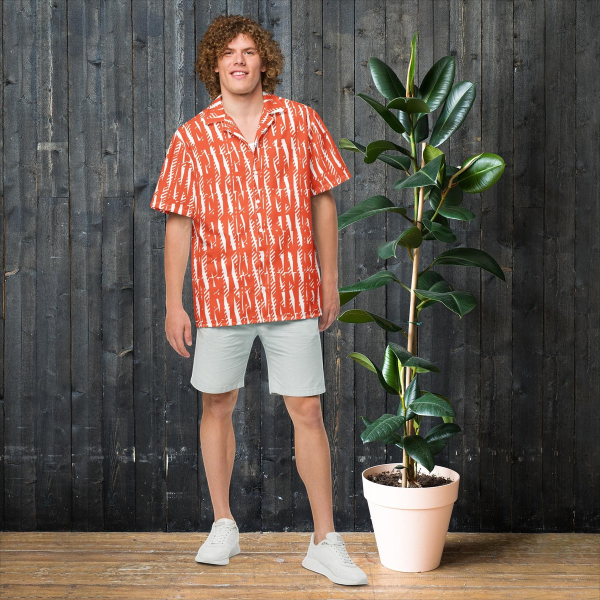 Good Wishes 365 unisex button shirt in orange with white abstract print, worn by a man with curly hair.