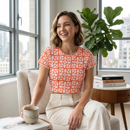 Good Wishes 365 woman wearing an orange and white geometric print crop tee while sitting in a bright modern living room