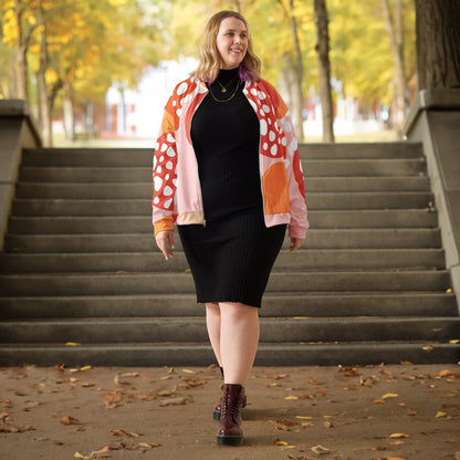 Good Wishes 365 unisex bomber jacket with orange strawberry print worn over a black dress on a park staircase