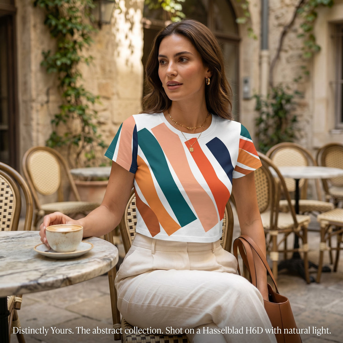 Good Wishes 365 crop tee with orange and teal wave print worn by a woman sitting at an outdoor cafe table