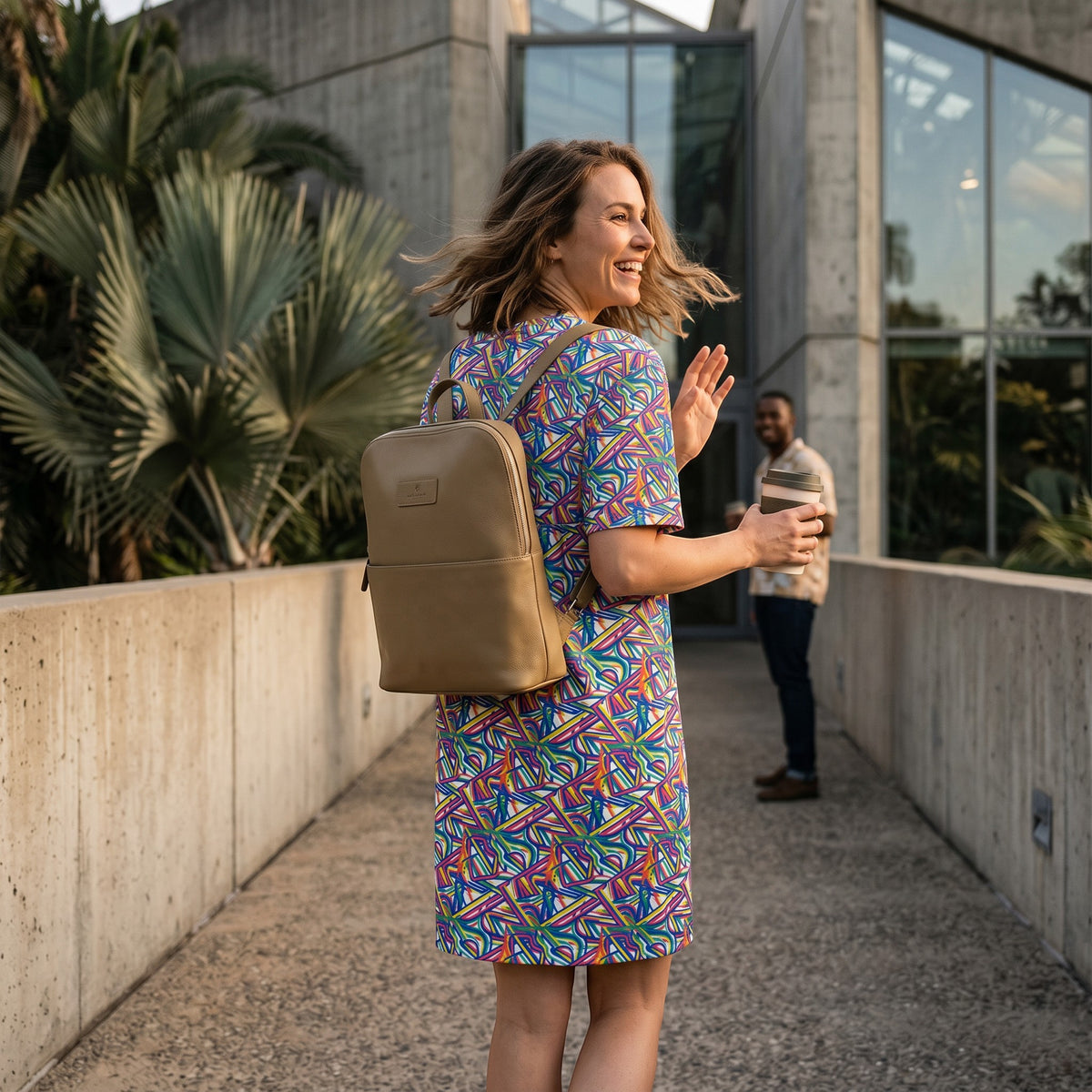 Good Wishes 365 oversize t-shirt dress with colorful abstract geometric print, worn by a woman with a tan backpack.