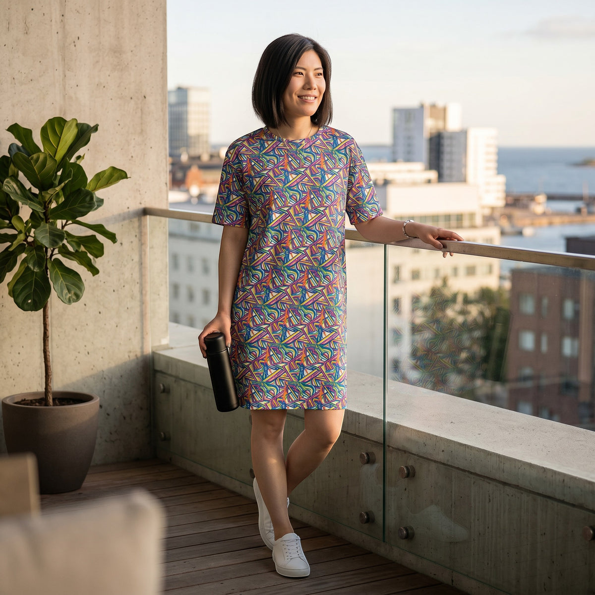 Good Wishes 365 oversize t-shirt dress with colorful abstract geometric print, worn by a woman on a city balcony.