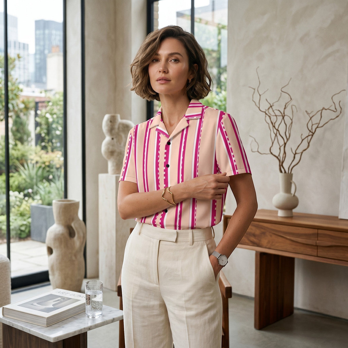 Good Wishes 365 retro pastel blush button-down shirt with magenta stripes, worn by a woman in a modern interior.