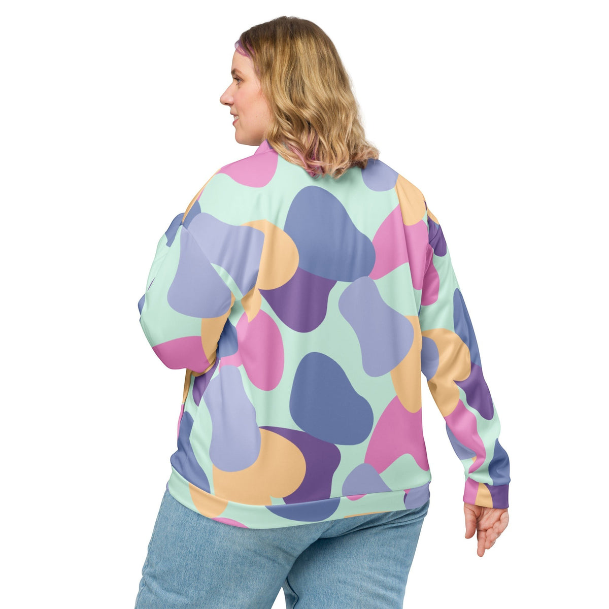 Good Wishes 365 unisex bomber jacket with an abstract pastel print in mint, lavender, peach, and violet on a woman.
