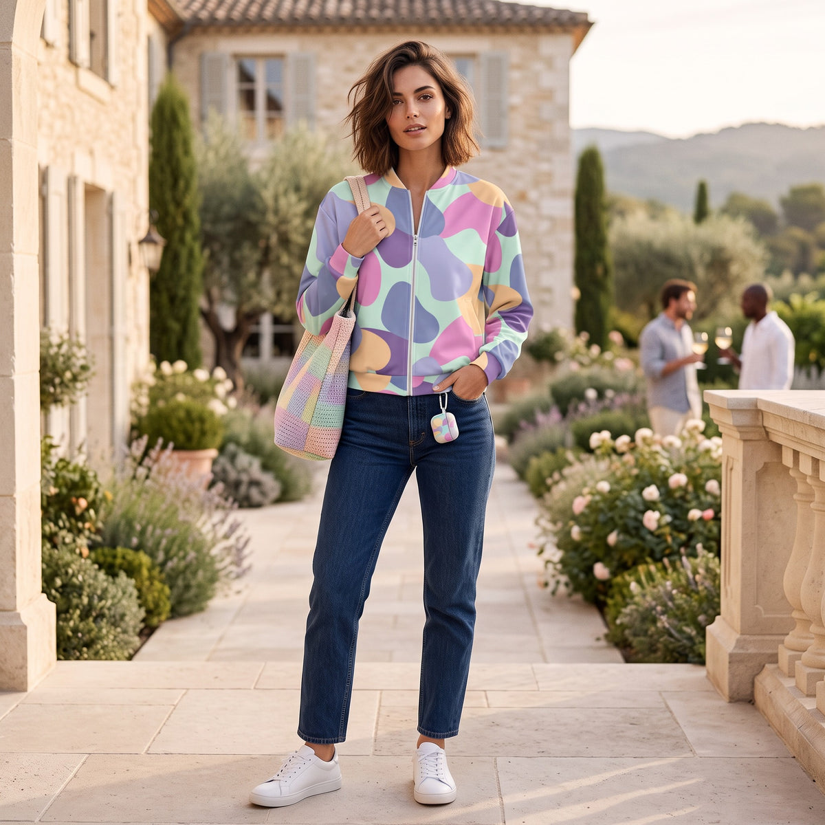 Good Wishes 365 unisex bomber jacket with pastel all-over print, worn by a woman with jeans and white sneakers.