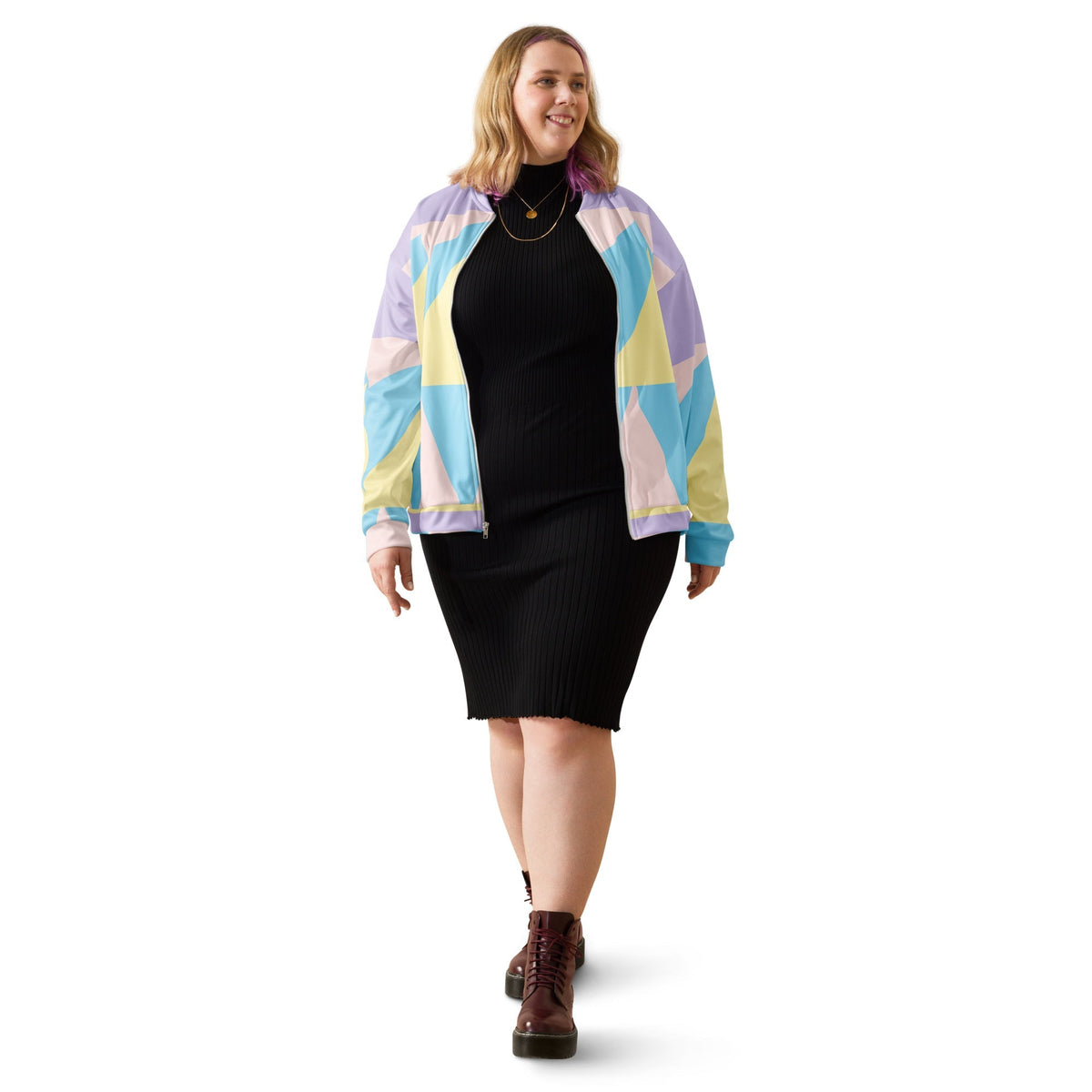 Good Wishes 365 unisex bomber jacket with pastel geometric print worn over a black ribbed dress by a smiling woman.