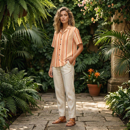 Good Wishes 365 retro pastel peach striped short sleeve button shirt worn by a woman in a lush garden setting.
