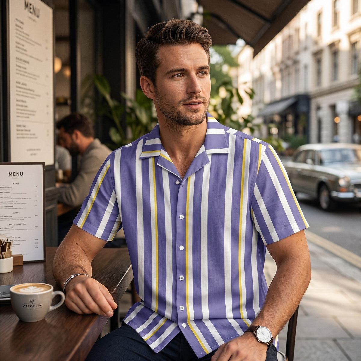 Good Wishes 365 men's periwinkle, white, and yellow vertical striped short sleeve camp collar shirt worn at a cafe.
