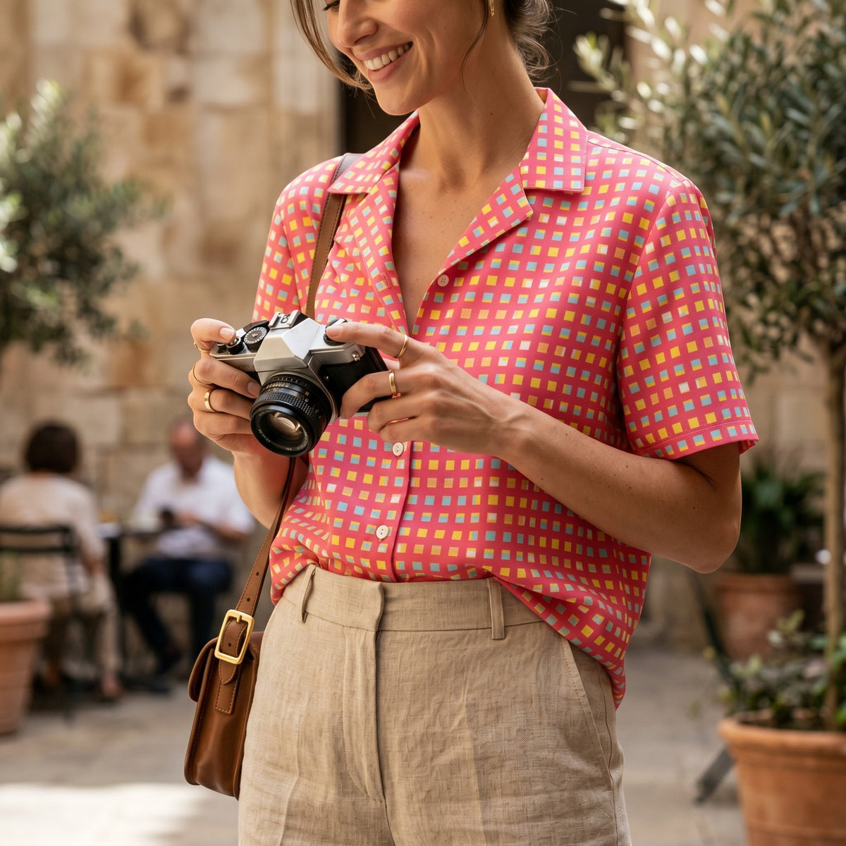 Good Wishes 365 pink checkered button-down shirt with UPF 50+ protection, worn by a woman holding a vintage camera.