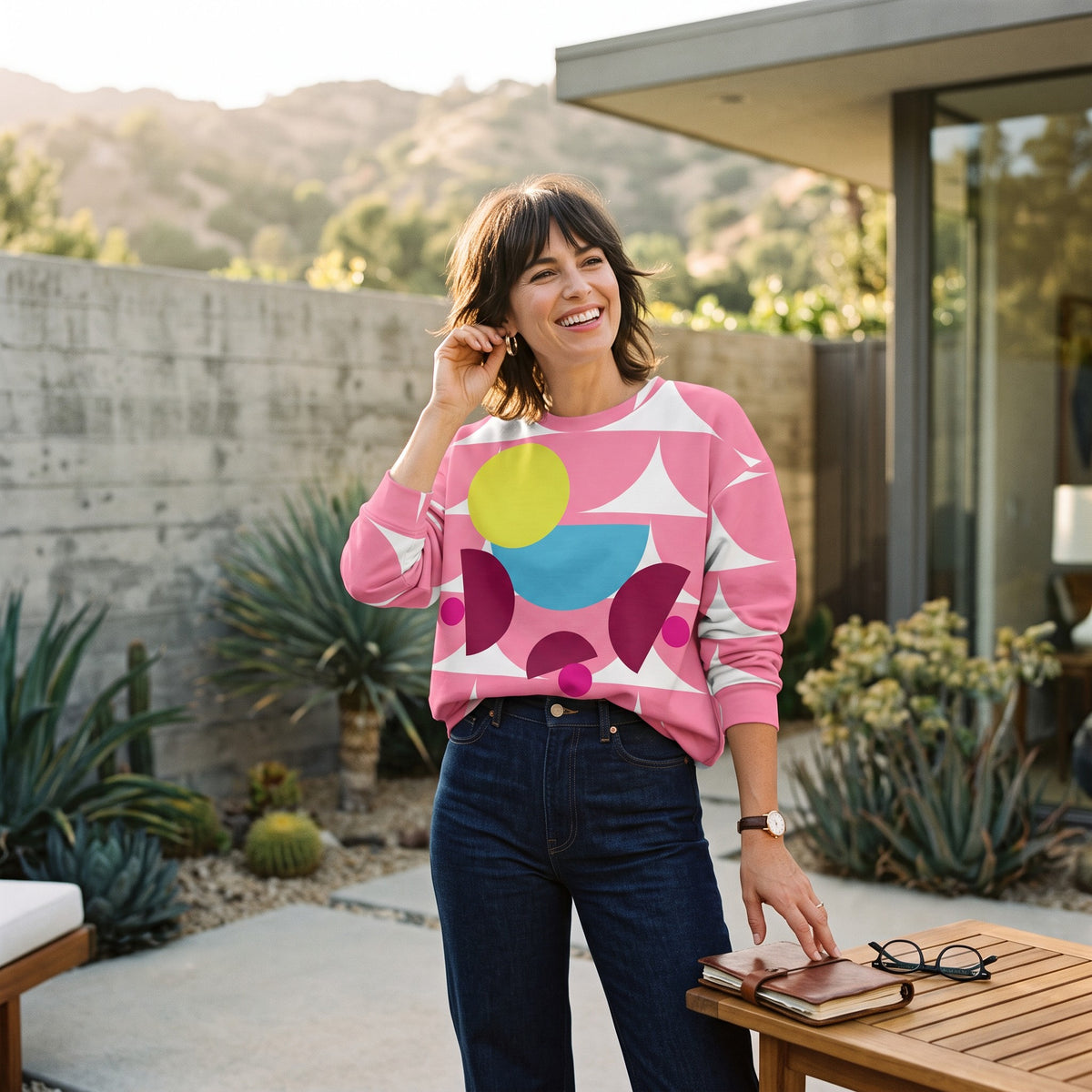 Good Wishes 365 pink recycled sweatshirt featuring a geometric mushroom graphic, worn by a smiling woman outdoors.