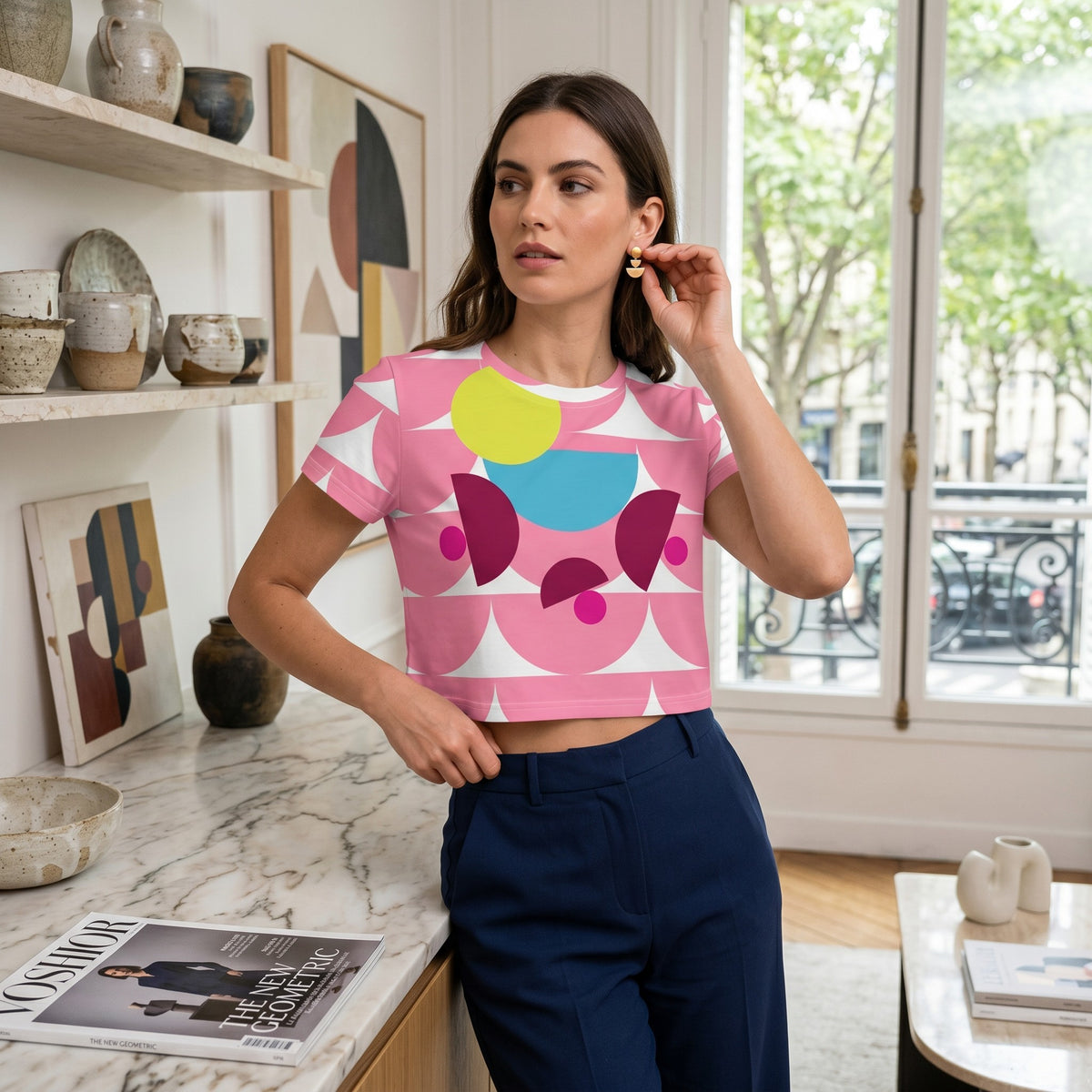 Good Wishes 365 pink crop tee with abstract mushroom print worn by a woman in a bright, modern apartment interior.