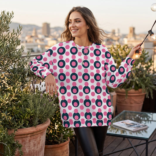 Good Wishes 365 recycled sweatshirt with pink and navy polka dot pop art print worn by a woman on a rooftop terrace