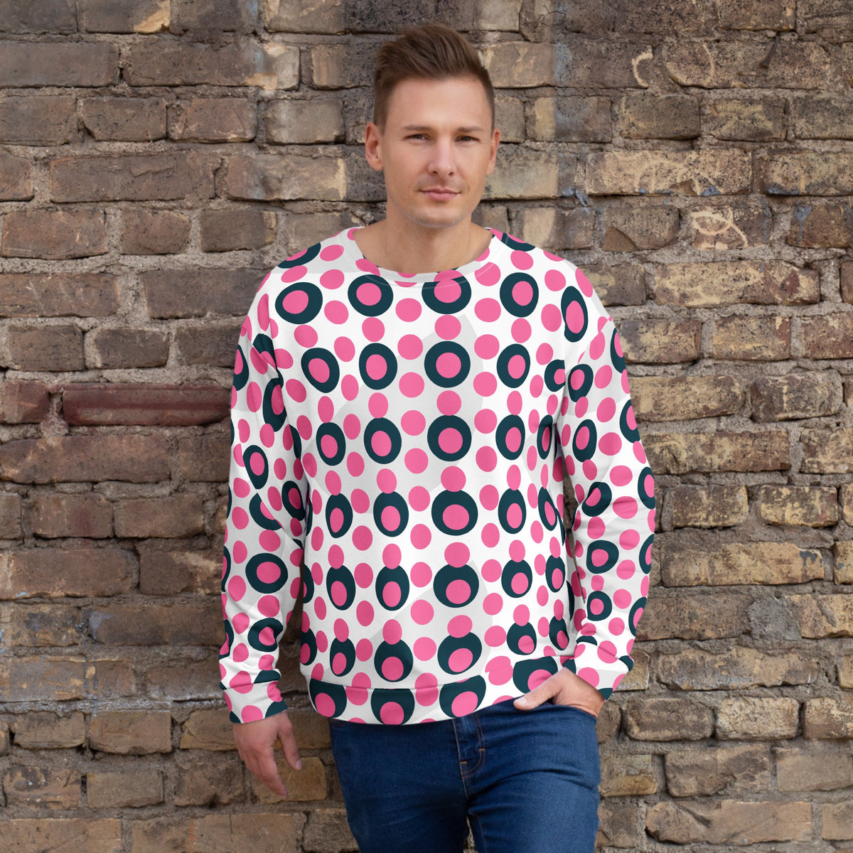 Good Wishes 365 unisex recycled sweatshirt with pink and charcoal polka dot print worn by a man against a brick wall