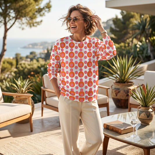 Good Wishes 365 woman wearing a pink and orange 70s pop art polka dot recycled sweatshirt on a sunny patio