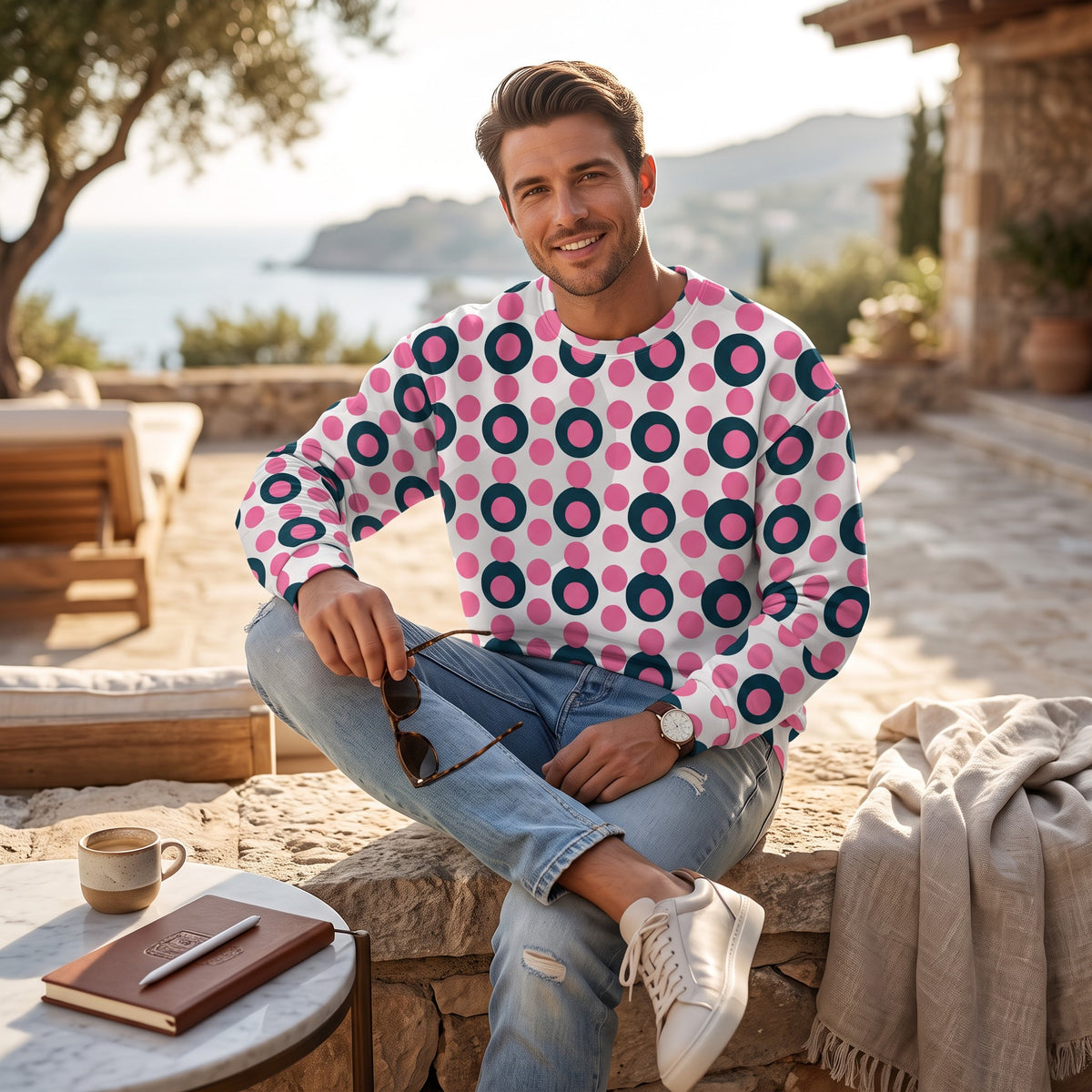 Good Wishes 365 unisex sweatshirt with rose pink and charcoal polka dot print, worn by a man on a sunny patio.