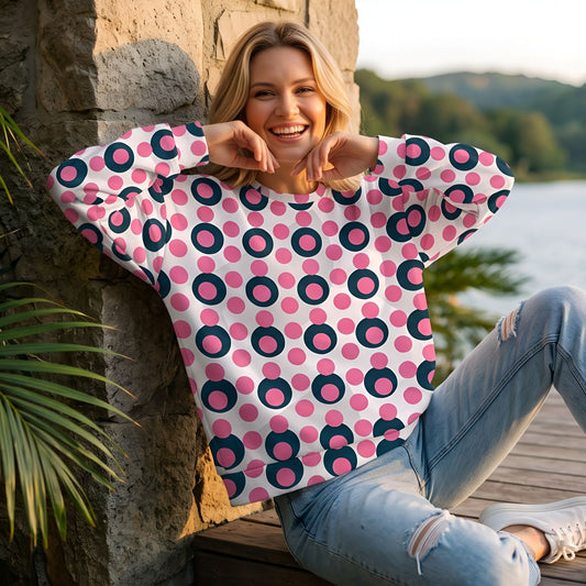 Good Wishes 365 recycled sweatshirt with 70s pop art pink and navy polka dot print worn by a woman on a wooden dock.