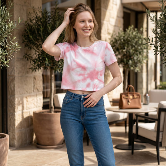 Good Wishes 365 pink tie-dye crop tee worn by a smiling woman with blue jeans in an outdoor cafe setting.