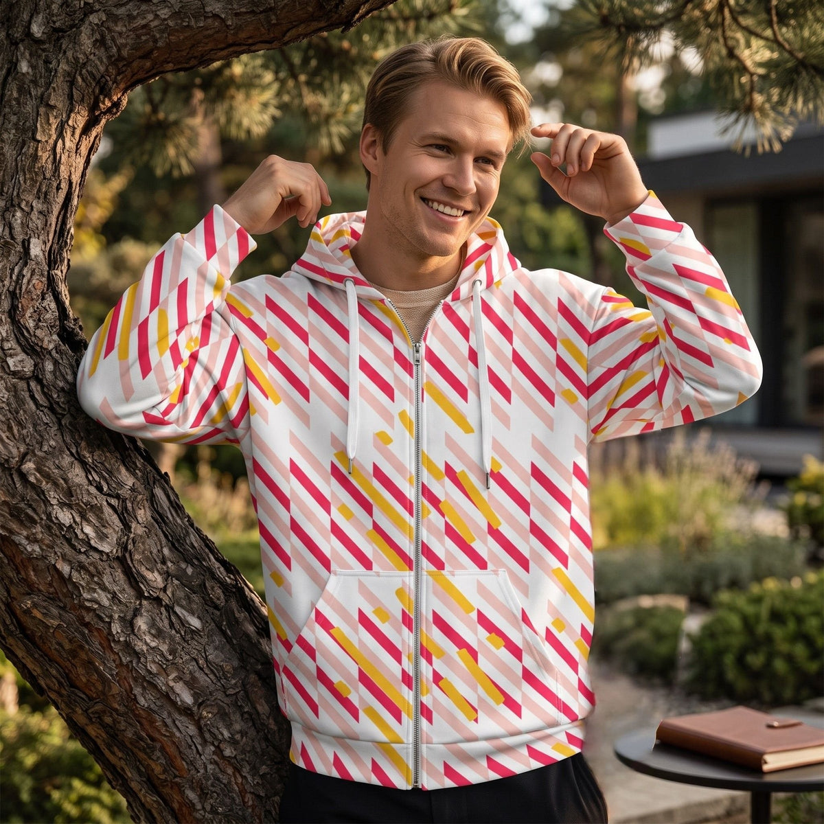 Good Wishes 365 unisex zip hoodie with pink and yellow geometric lines, worn by a smiling man outdoors.