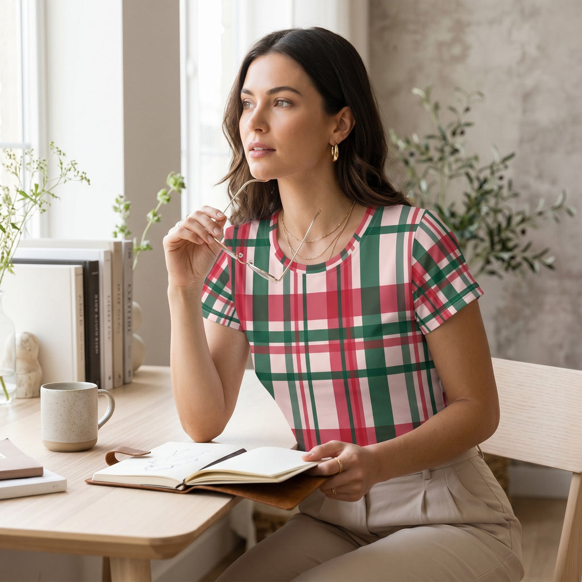 A woman wearing a Good Wishes 365 red and green plaid crop tee while sitting at a desk with a notebook.