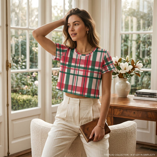 A woman wearing a Good Wishes 365 all-over plaid print crop tee in red, green, and white, styled with cream trousers.