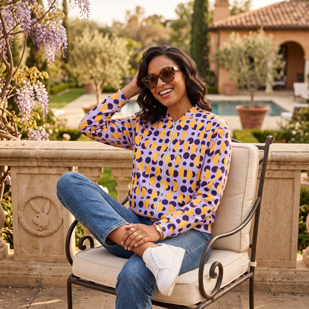 Good Wishes 365 purple bomber jacket with yellow semi-circles and polka dots, worn by a smiling woman outdoors.