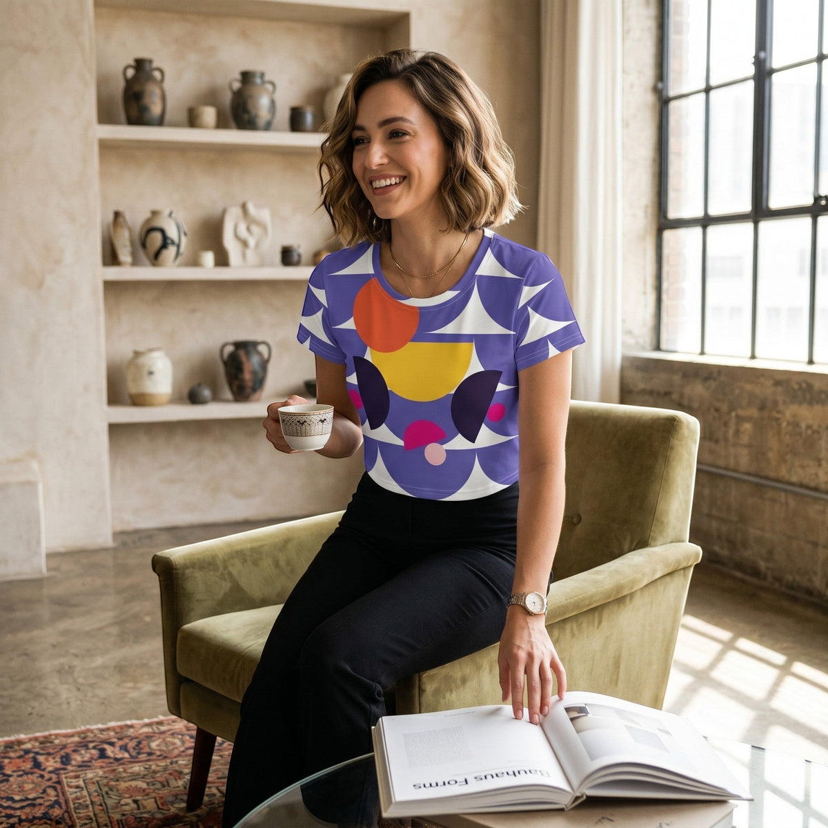 Good Wishes 365 purple crop tee with geometric mushroom graphic worn by a woman sitting in a green armchair