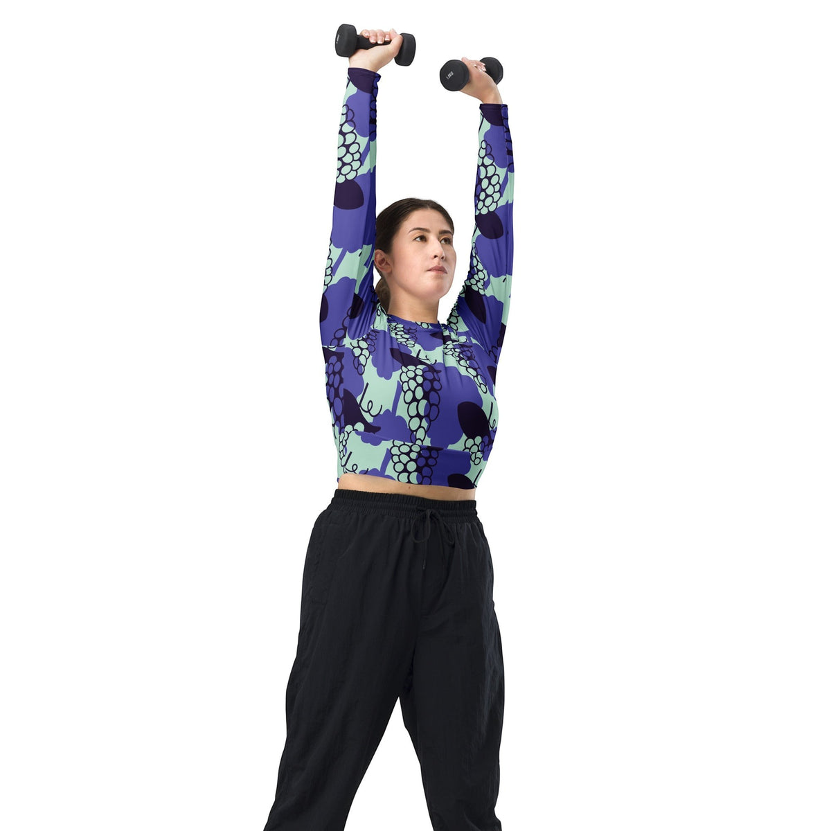 A woman wearing a Good Wishes 365 purple and mint grape-print long-sleeve crop top while lifting small dumbbells.