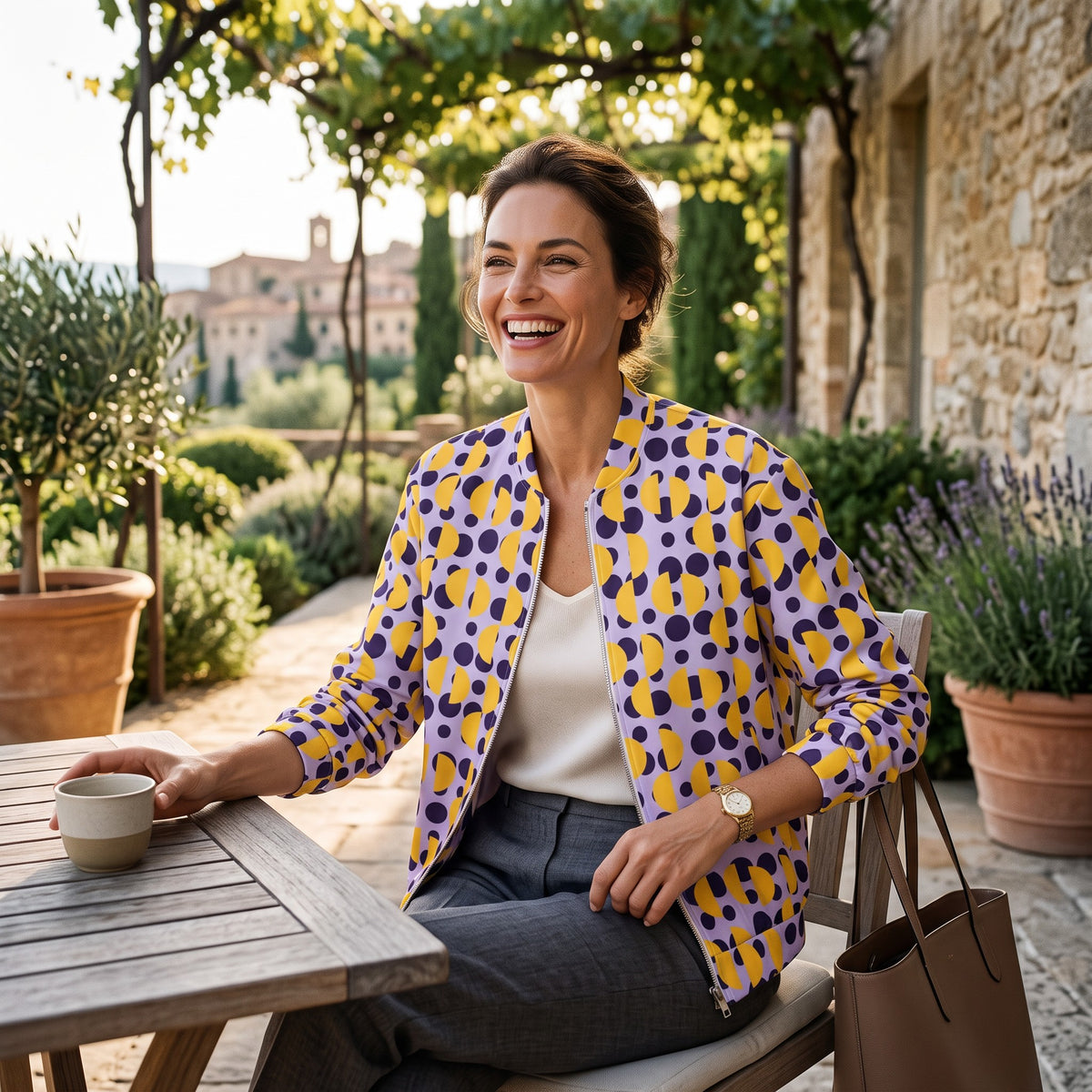 Good Wishes 365 unisex bomber jacket with purple and yellow polka dot print worn by a smiling woman outdoors
