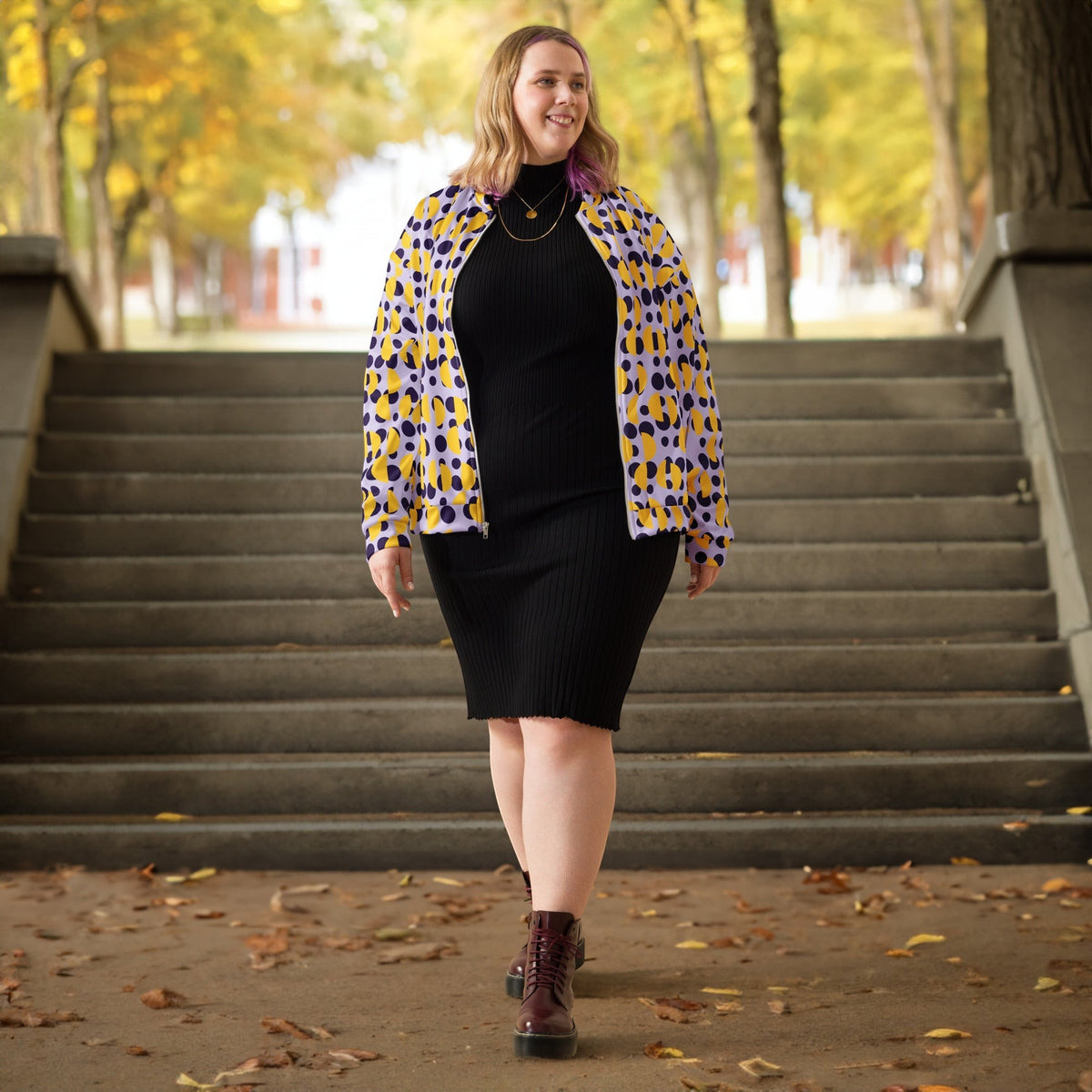 Good Wishes 365 bomber jacket with purple polka dots and yellow semi-circles worn by a woman over a black dress