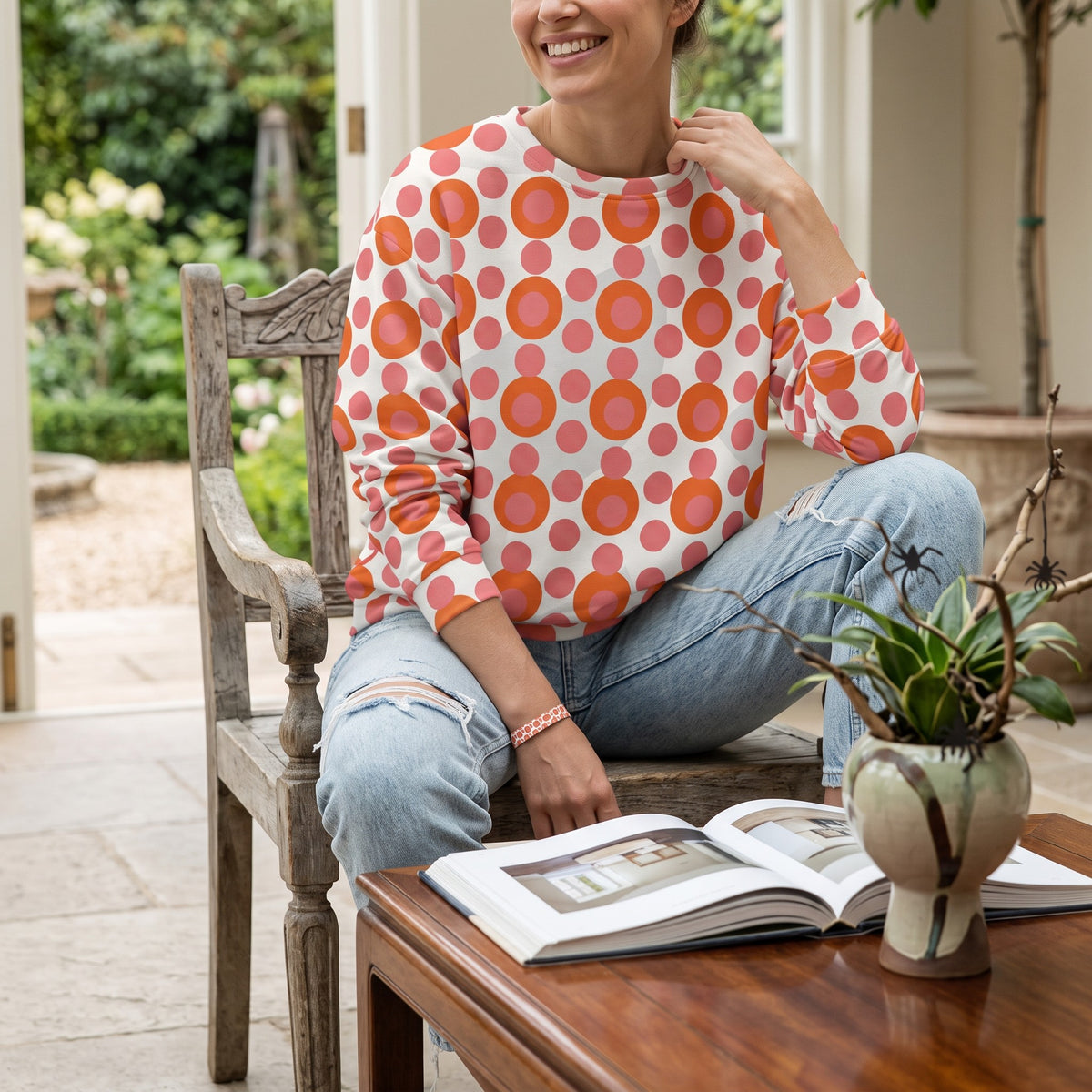 Good Wishes 365 recycled sweatshirt with a 70s pop art pink and orange polka dot print worn by a smiling woman