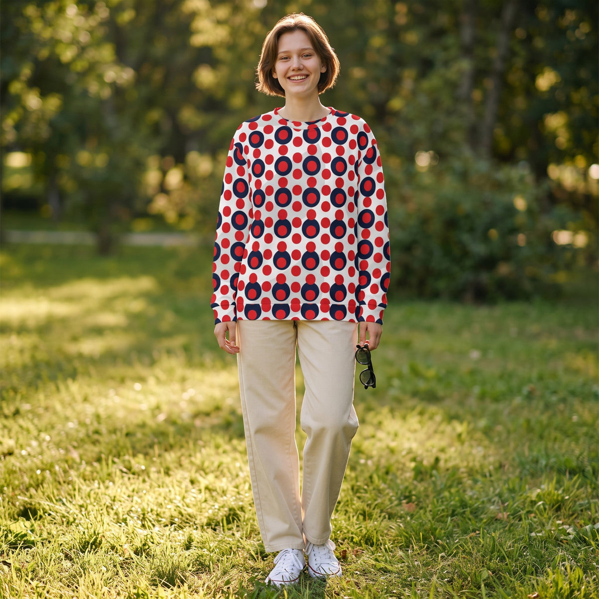 Good Wishes 365 women's recycled sweatshirt with a 70s red and navy polka dot print, worn by a smiling woman outdoors.