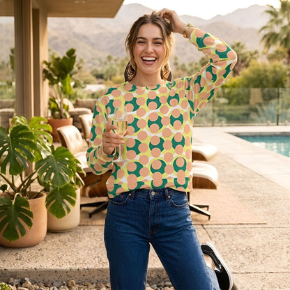 A woman wearing a Good Wishes 365 recycled sweatshirt with a 70s pop art pattern in pink, yellow, and forest green.