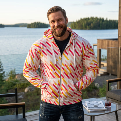 Good Wishes 365 recycled zip hoodie with pink and yellow geometric lines, worn by a smiling man on a lakeside deck.