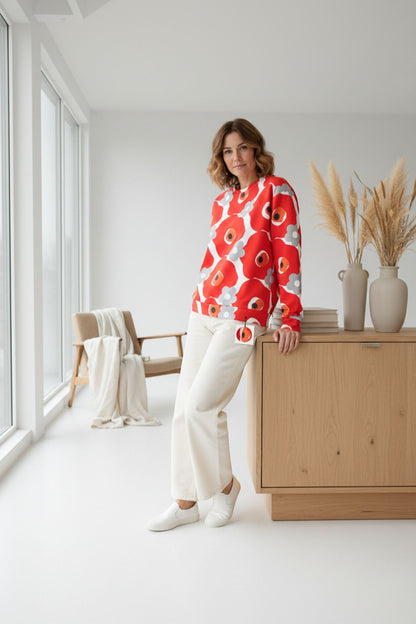 Good Wishes 365 unisex sweatshirt with red and gray floral print, worn by a woman in a bright, modern living space.