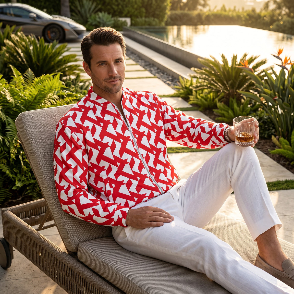 A man wearing a Good Wishes 365 red and white geometric maze print bomber jacket while relaxing by a pool.