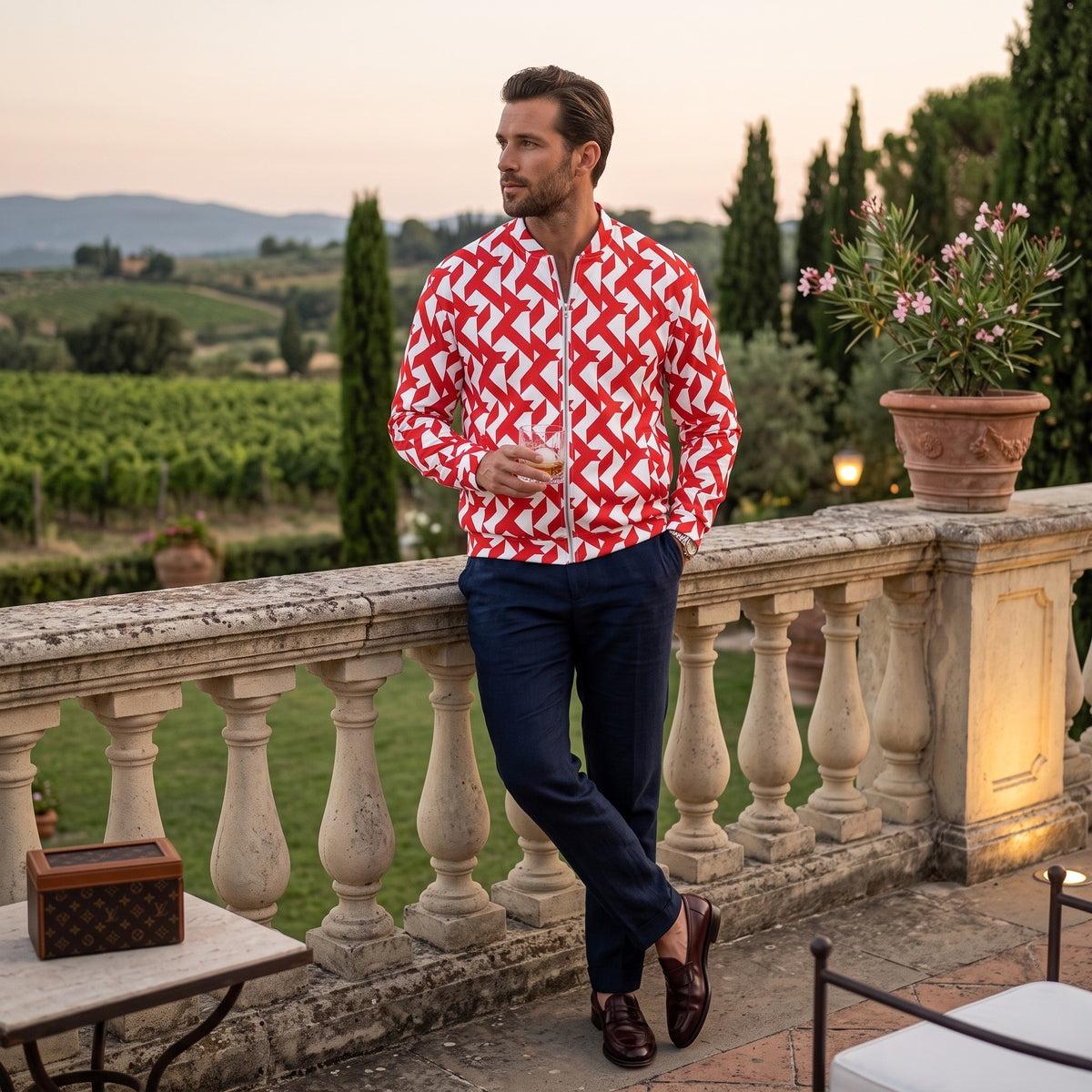 Good Wishes 365 red and white geometric maze print bomber jacket worn by a man on a scenic stone terrace.