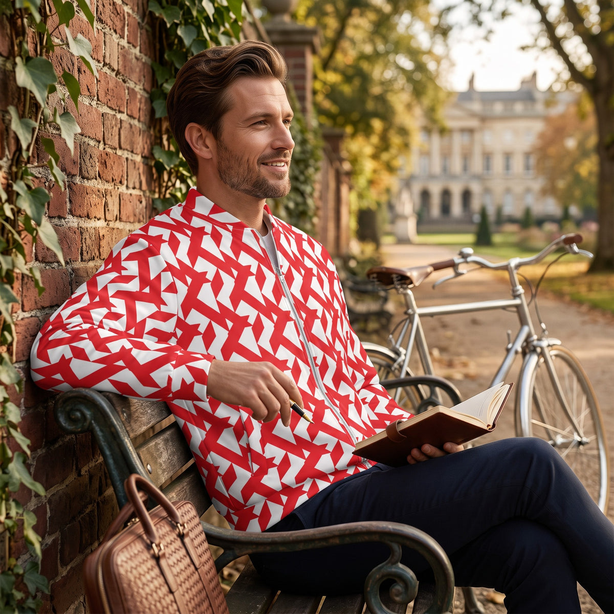 Good Wishes 365 red and white geometric maze print bomber jacket worn by a man sitting on a park bench with a notebook