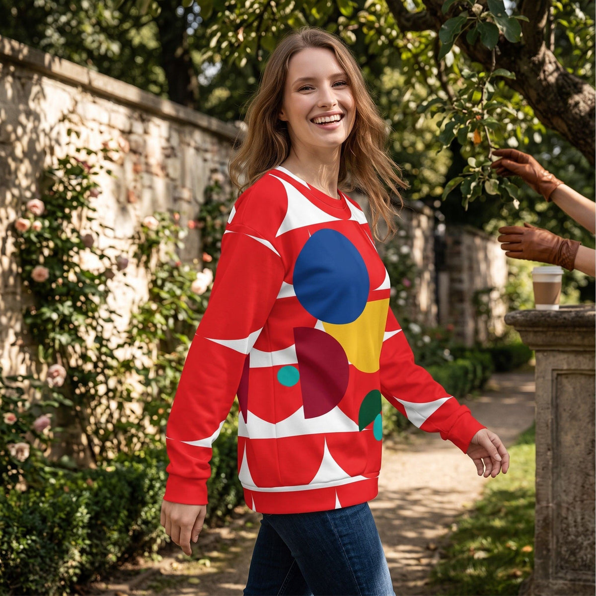 Good Wishes 365 red recycled sweatshirt with geometric mushroom print worn by a smiling woman in a garden setting
