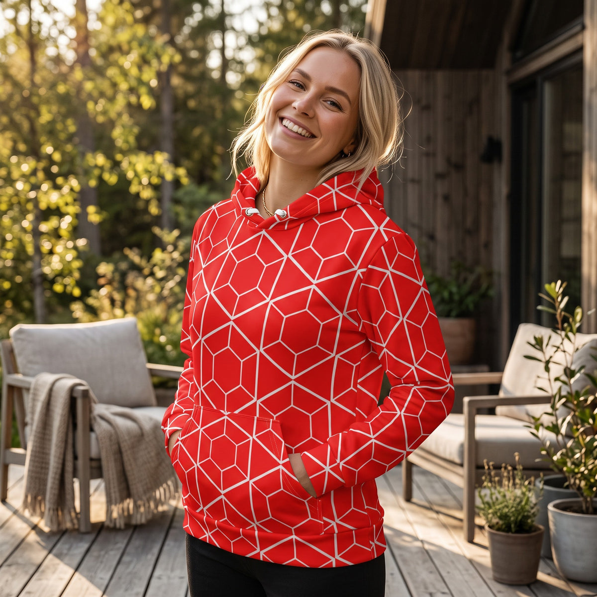 Good Wishes 365 red recycled hoodie with white geometric hexagon pattern, worn by a smiling woman on a wooden deck.