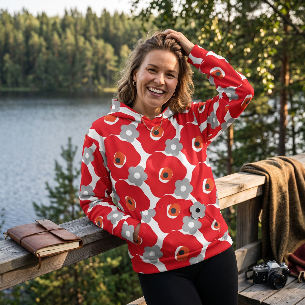 Good Wishes 365 red and gray floral print recycled hoodie worn by a smiling woman outdoors by a lake